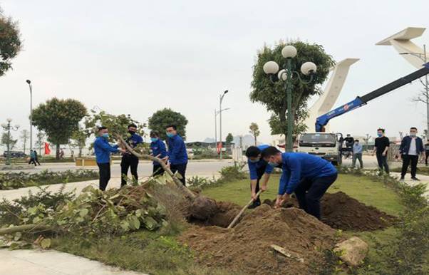 A group of people in blue uniforms digging a hole in the ground

Description automatically generated